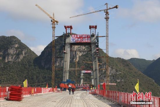 11月22日，正在建設(shè)中的峰林特大橋。當(dāng)日，隨著1470噸裝配化預(yù)制中橫梁提升到位，貴州省黔西南布依族苗族自治州興義環(huán)城高速公路峰林特大橋4號(hào)主塔中橫梁成功吊裝，由此刷新了山區(qū)峽谷橋梁預(yù)制吊裝混凝土構(gòu)件重量世界記錄。峰林特大橋是屬全線控制性工程。大橋跨越馬嶺河峽谷，全長(zhǎng)1163米，主跨采用550米懸索橋，橋面離谷底364.2米，是中國(guó)山區(qū)第一座大跨徑鋼混疊合梁懸索橋。中新社記者 瞿宏倫 攝