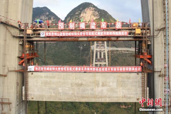 11月22日，隨著1470噸裝配化預(yù)制中橫梁提升到位，貴州省黔西南布依族苗族自治州興義環(huán)城高速公路峰林特大橋4號(hào)主塔中橫梁成功吊裝，由此刷新了山區(qū)峽谷橋梁預(yù)制吊裝混凝土構(gòu)件重量世界記錄。峰林特大橋是屬全線控制性工程。大橋跨越馬嶺河峽谷，全長(zhǎng)1163米，主跨采用550米懸索橋，橋面離谷底364.2米，是中國(guó)山區(qū)第一座大跨徑鋼混疊合梁懸索橋。中新社記者 瞿宏倫 攝